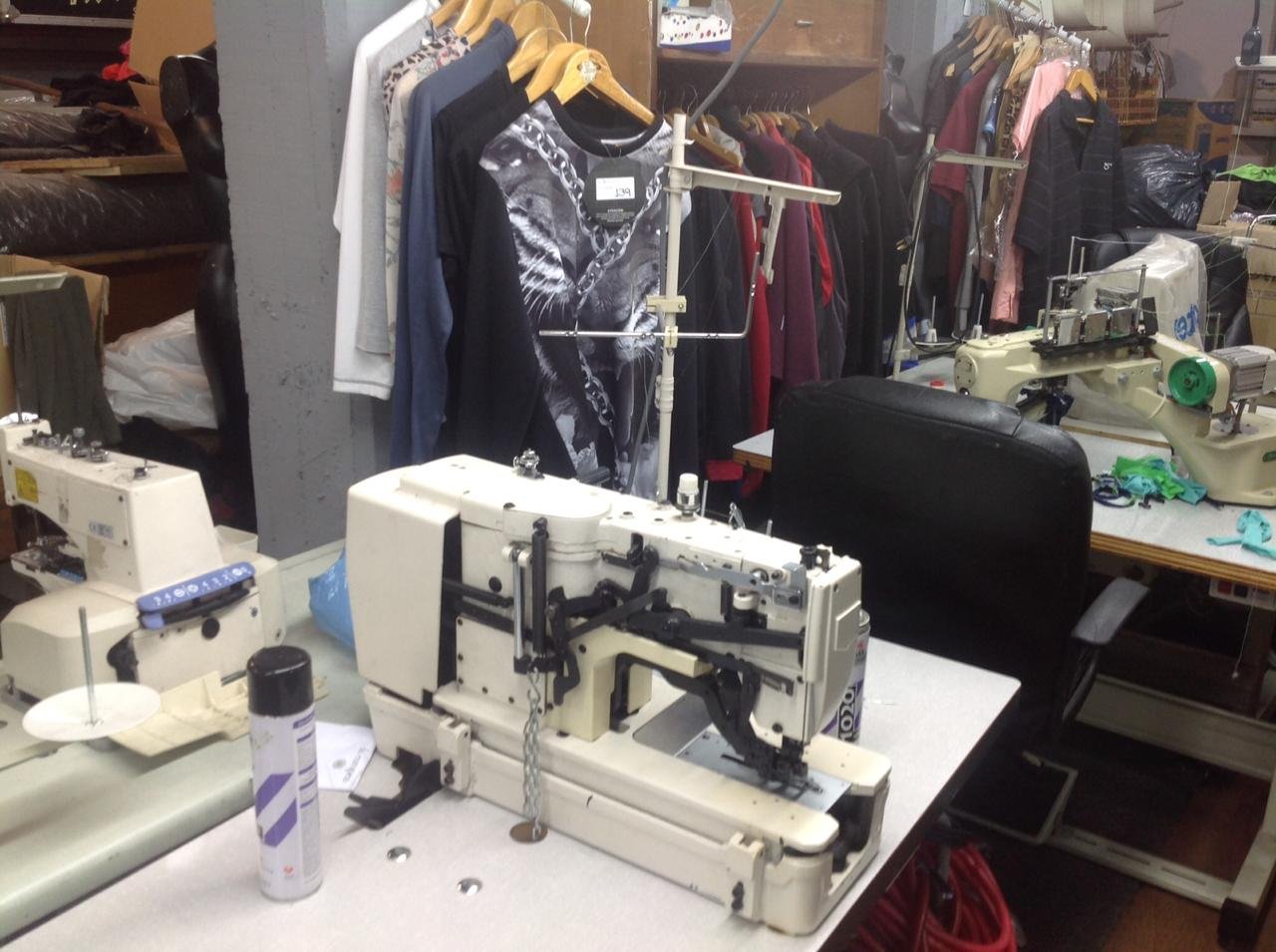 Prendas terminadas en percha junto a máquina de costura